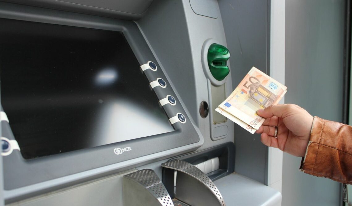 Eine Person am Land behebt Geld von einem Bankomaten im Ort.