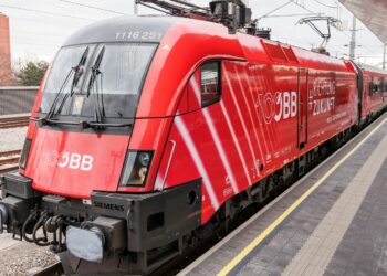 Öffentliches Verkehrsmittel (ÖBB-Zug) fährt in Bahnhof ein, damit Passagiere zusteigen können.