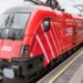 Öffentliches Verkehrsmittel (ÖBB-Zug) fährt in Bahnhof ein, damit Passagiere zusteigen können.