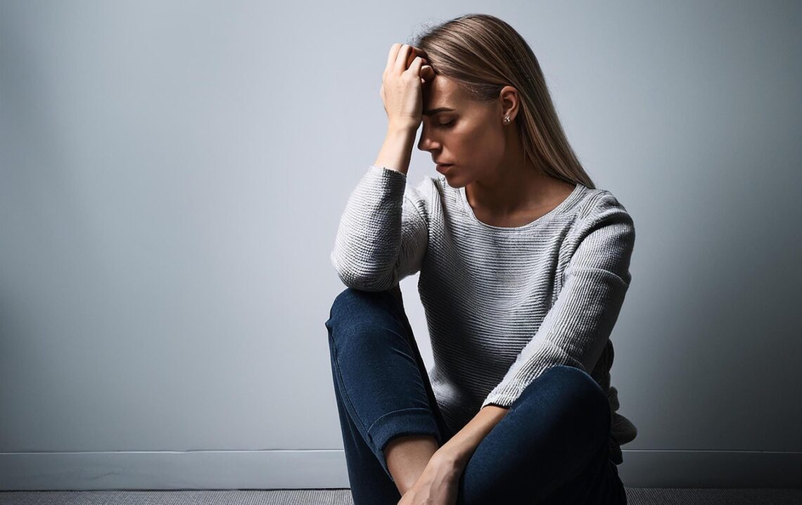 Frau sitzt nachdenklich und traurig am Boden