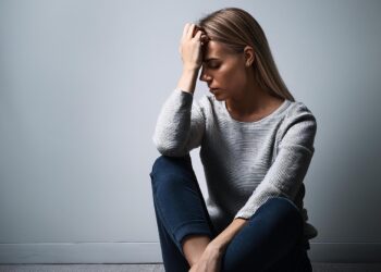 Frau sitzt nachdenklich und traurig am Boden