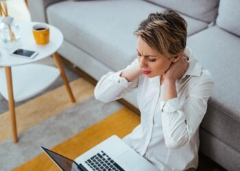 Symbolbild zeigt eine erschöpfte Frau mit Laptop.