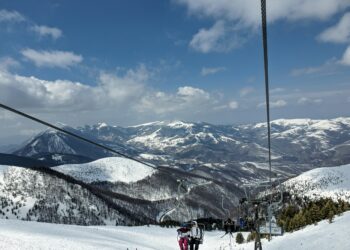 Das Symbolbild eines Skigebiets zeigt Menschen in einem Sessellift.