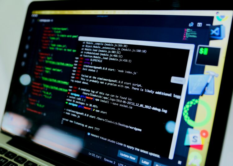 Laptop mit grünem Quellcode auf schwarzem Bildschirm mit Neon-Effekt.