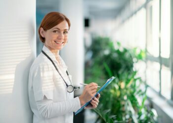 Eine junge, lächelnde Ärztin mit Stethoskop im Krankenhaus