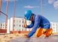 Ein Mann in Arbeitskleidung arbeitet auf einer Baustelle.
